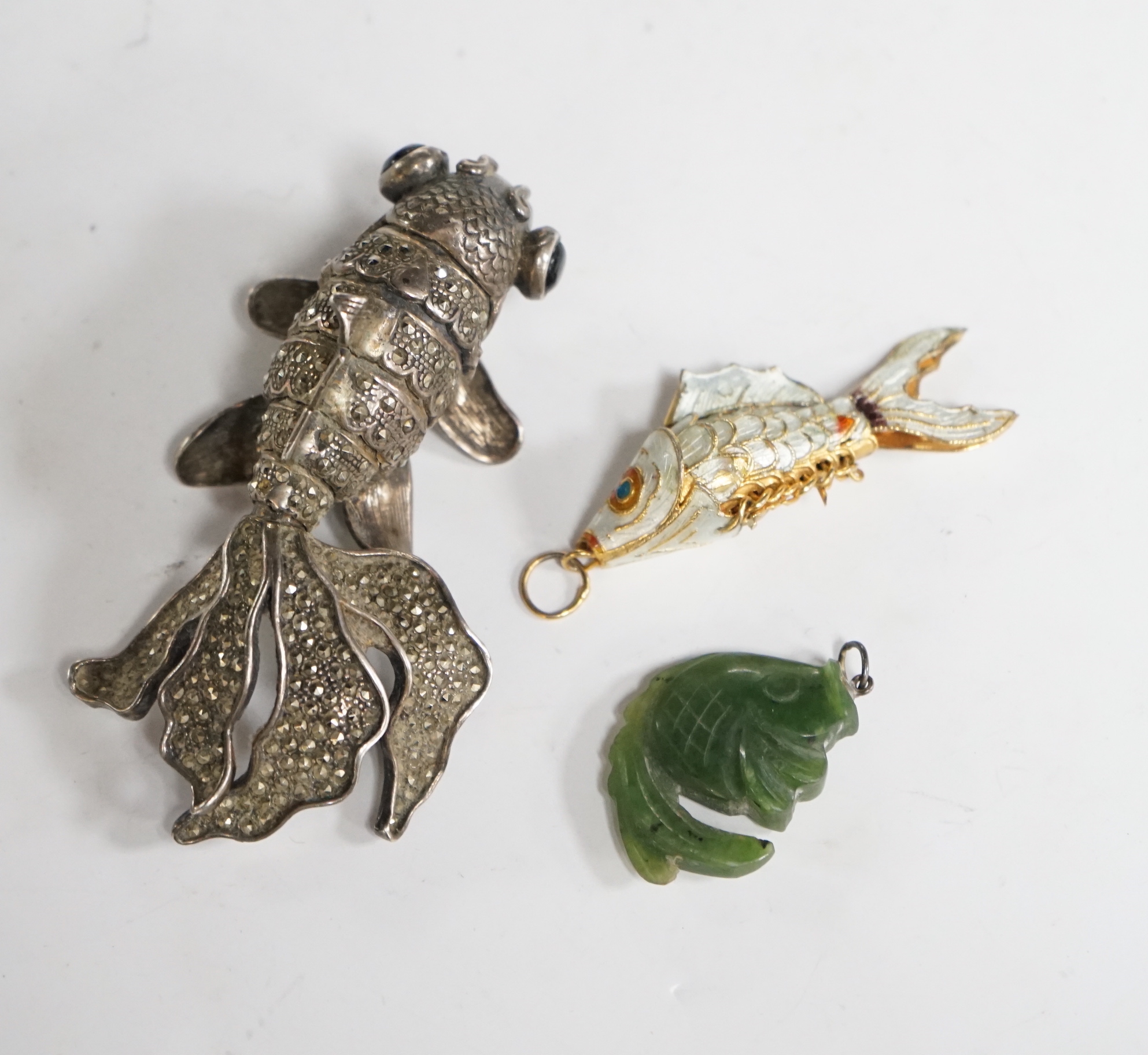 A Chinese? white metal, marcasite and cabochon set articulated model of a telescope goldfish?, 8cm, a gilt white metal and enamel articulated fish charm and a hardstone fish charm.